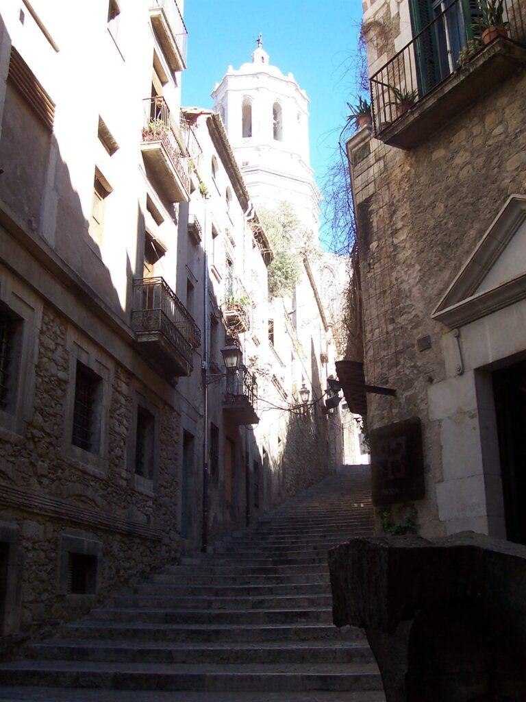 Escalinata de piedra en el Call de Girona, el antiguo barrio judío, con la torre de la catedral al fondo.