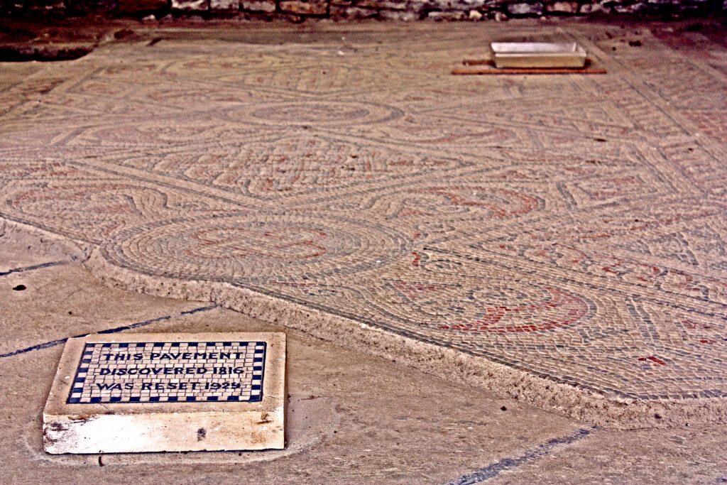 Mosaico geometrico de una villa romana britanica, con teselas rojas, blancas y azul grisaceo
