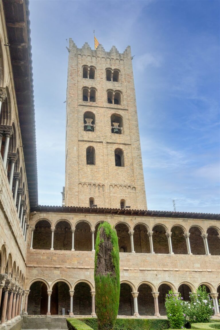 Torre campanario y claustro románico del Monestir de Santa Maria de Ripoll, con la senyera ondeando en lo alto.